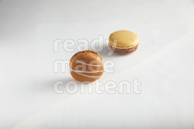 45º Shot of of two assorted Brown Irish Cream, and Yellow, and Brown Chai Latte macarons on white background