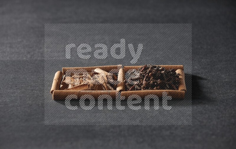 2 squares of cinnamon sticks full of cloves and cinnamon on black flooring
