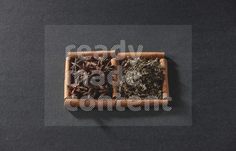 2 squares of cinnamon sticks full of star anise and dried basil on black flooring