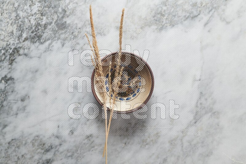 Wheat stalks on decorative pottery plate on grey marble background