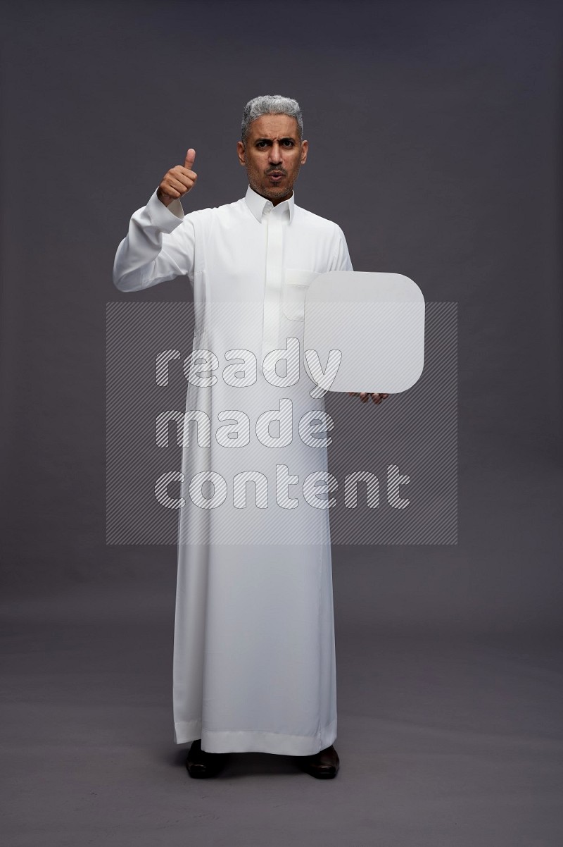 Saudi man wearing thob standing holding social media sign on gray background