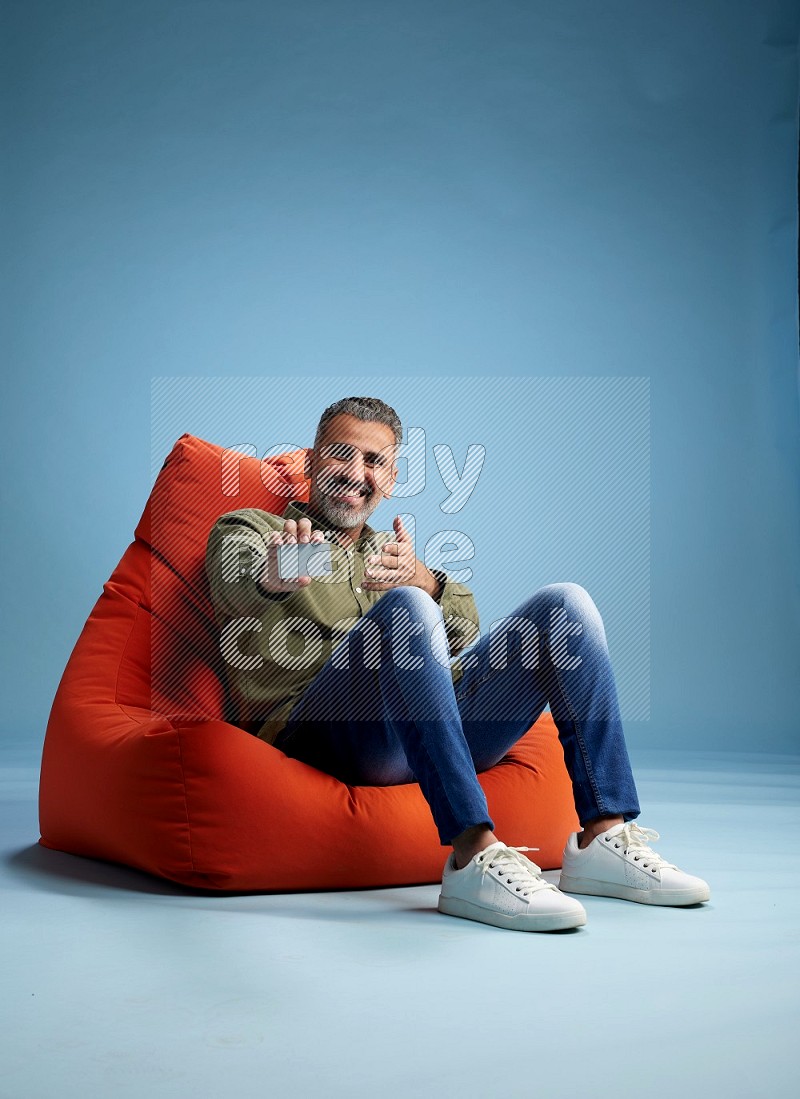 A man sitting on an orange beanbag and holding ATM card