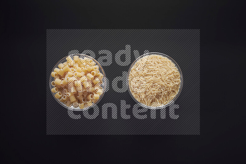 Different pasta types in glass bowls on black background