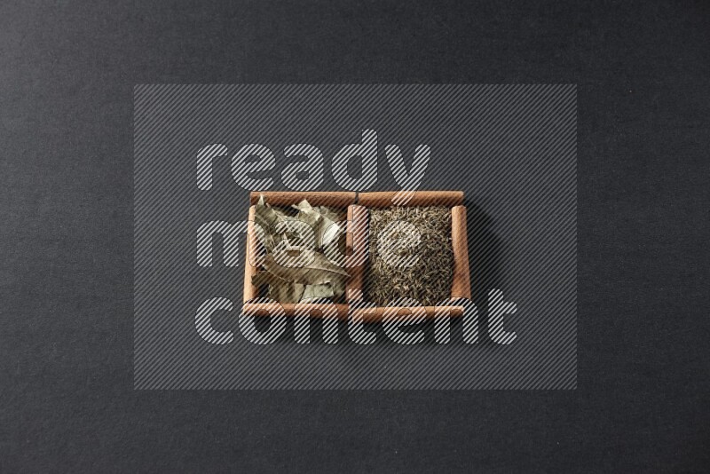 مربعان من أعواد القرفة ممتلئان بحبوب الكمون وأوراق الغار علي خلفية سوداء