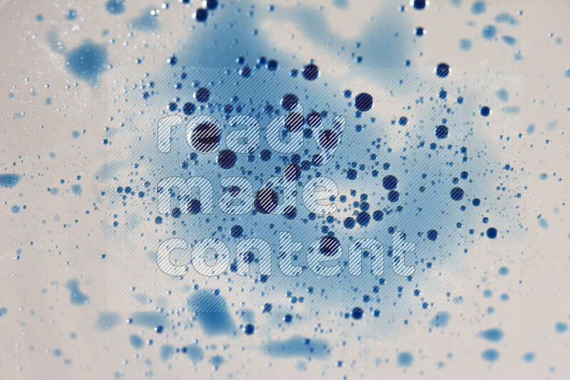 Close-ups of abstract blue watercolor drops on oil Surface on white background