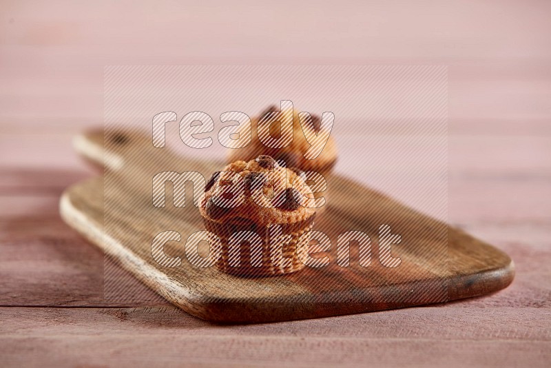 Vanilla mini cupcake topped with chocolate chips on a wooden board