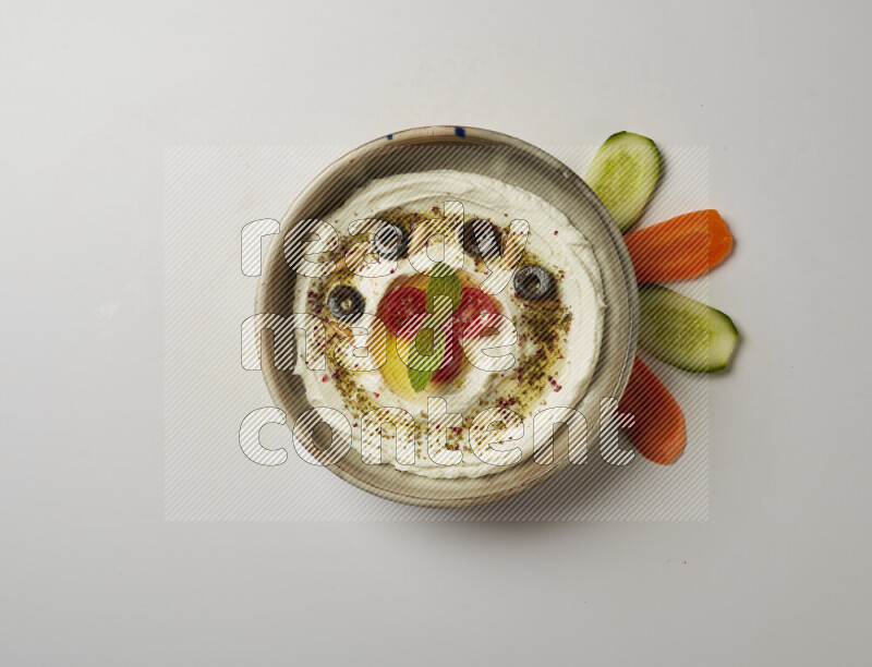 Lebnah garnished with cherry tomato, mint, olives & pine nuts in a grey pottery plate on a white background