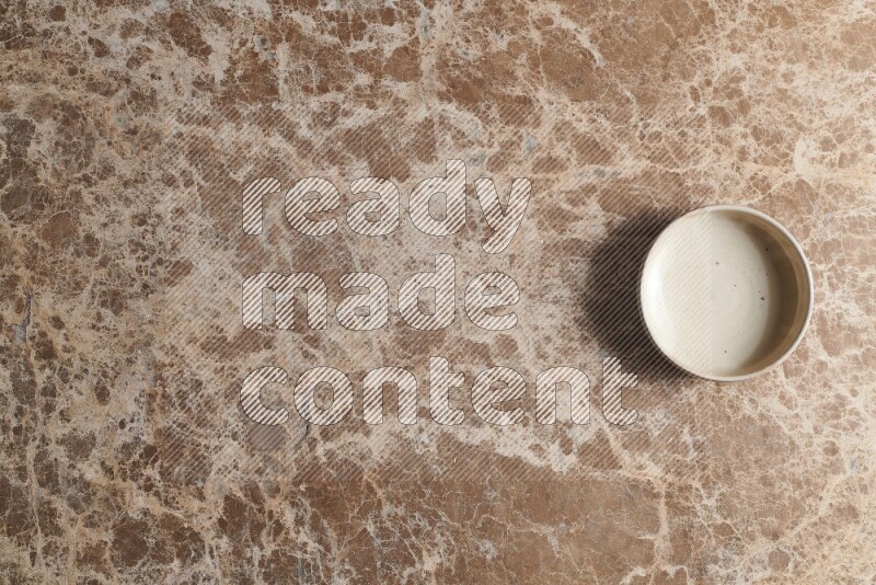 A white pottery bowl on beige marble background