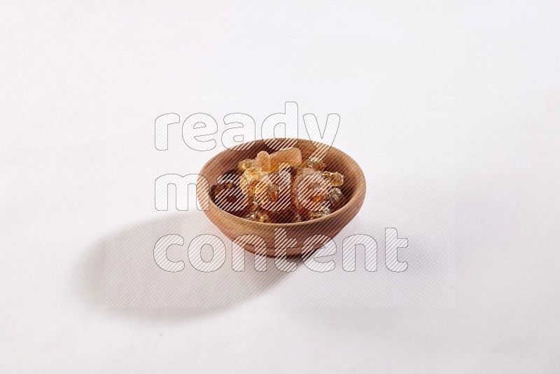 A wooden bowl full of gum arabic on a white flooring in different angles
