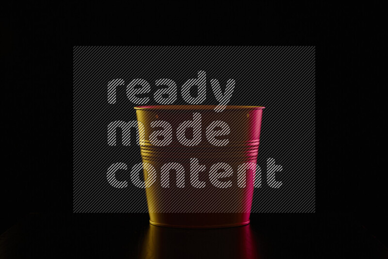 A plant pot with colored rim light against black background