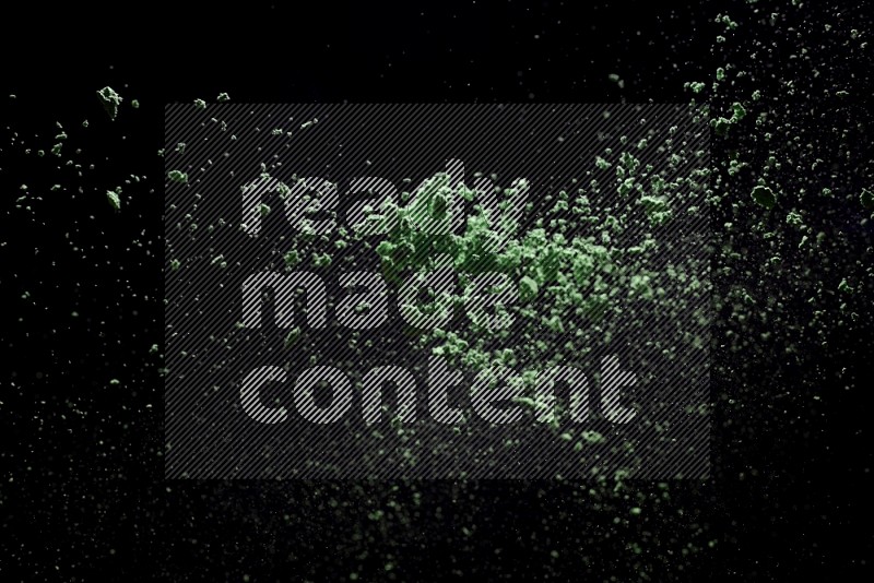 Green powder explosion on black background