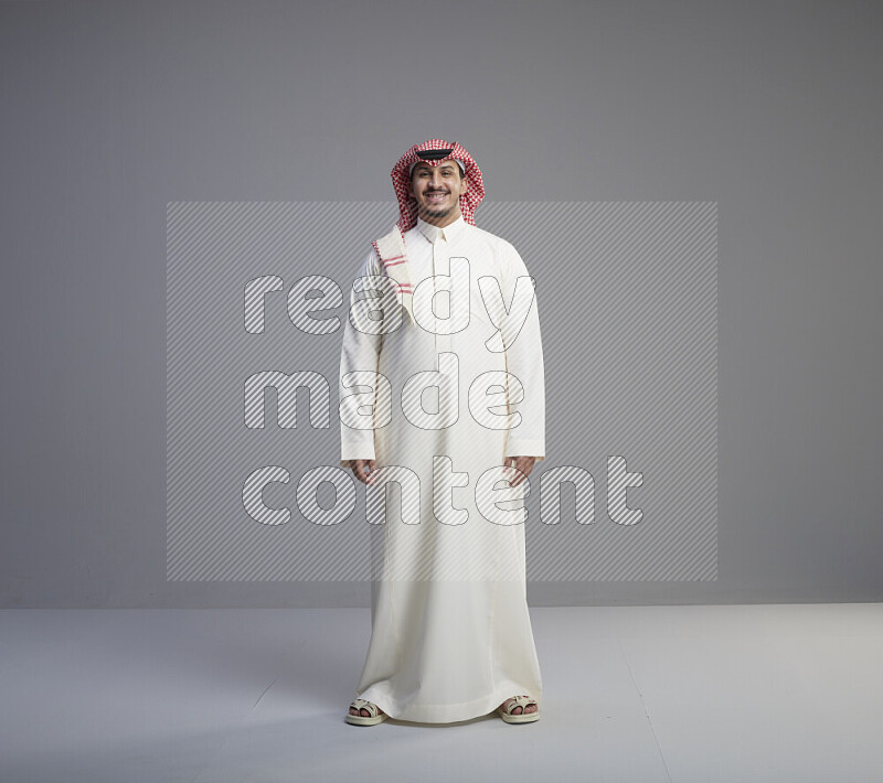 رجل سعودي يرتدي ثوب ابيض وشماغ احمر يشير بيده