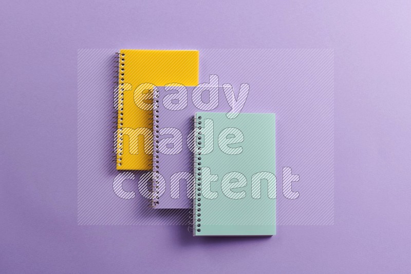 Multicolored notebooks on purple background (Back to school)