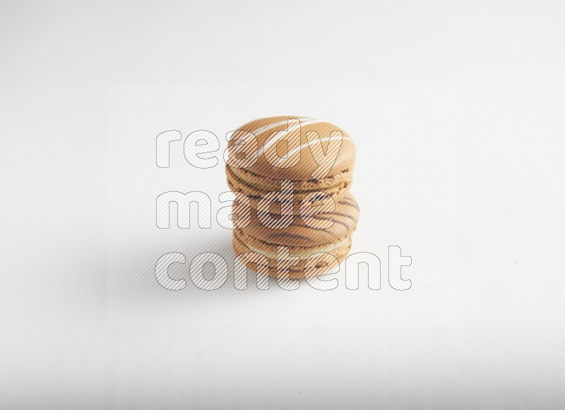 45º Shot of of two assorted Brown Irish Cream, and light brown  Almond Cream macarons on white background