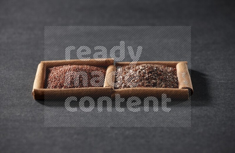 مربعان من أعواد القرفة ممتلئان بحب الرشاد وبذور الكتان علي خلفية سوداء