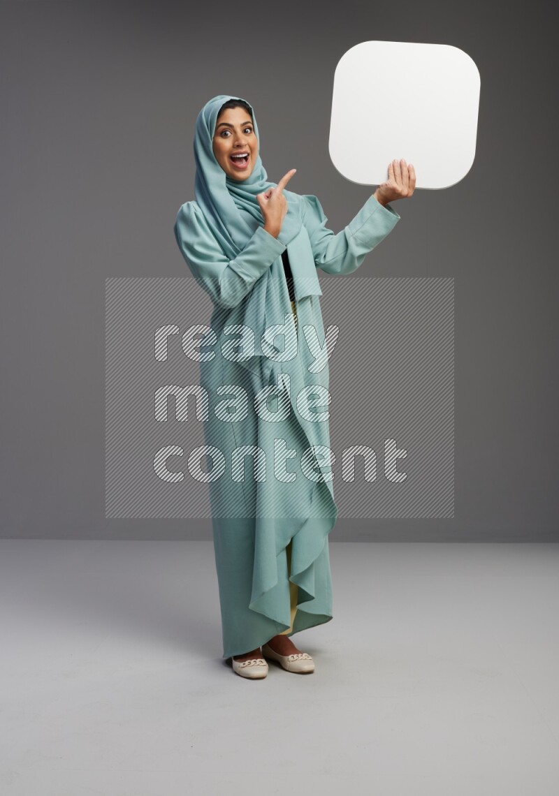 Saudi Woman wearing Abaya standing holding social media sign on Gray background