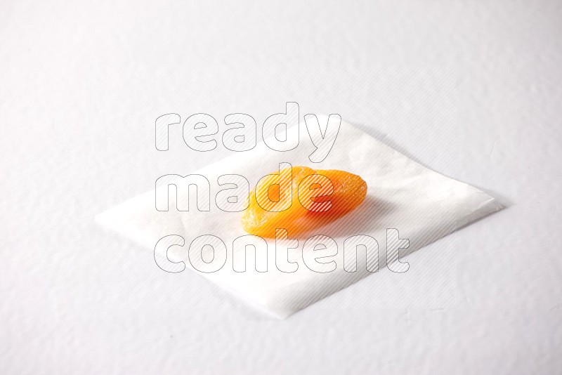 Two dried apricots on a piece of paper on a white background in different angles