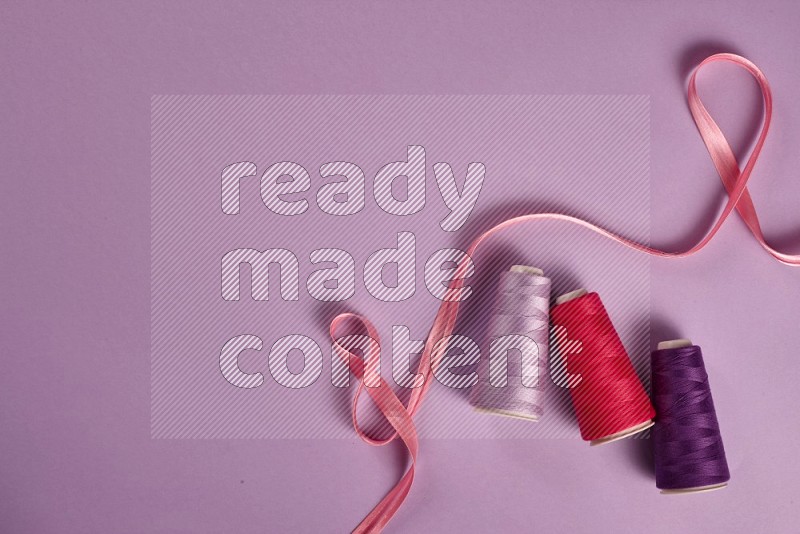 Pink sewing supplies on purple background