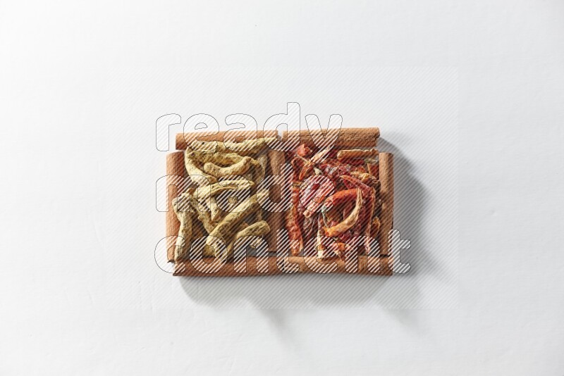 2 squares of cinnamon sticks full of dried red chilis and turmeric fingers on white flooring