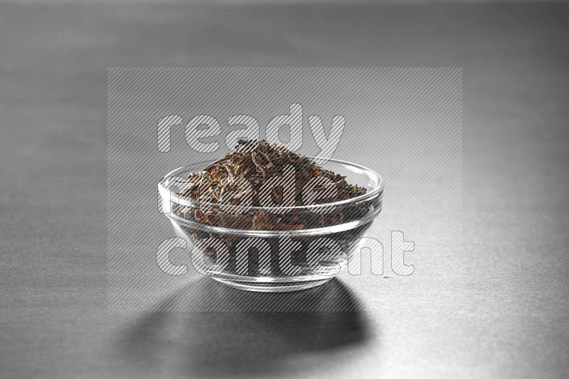 A glass bowl full of basil on black flooring