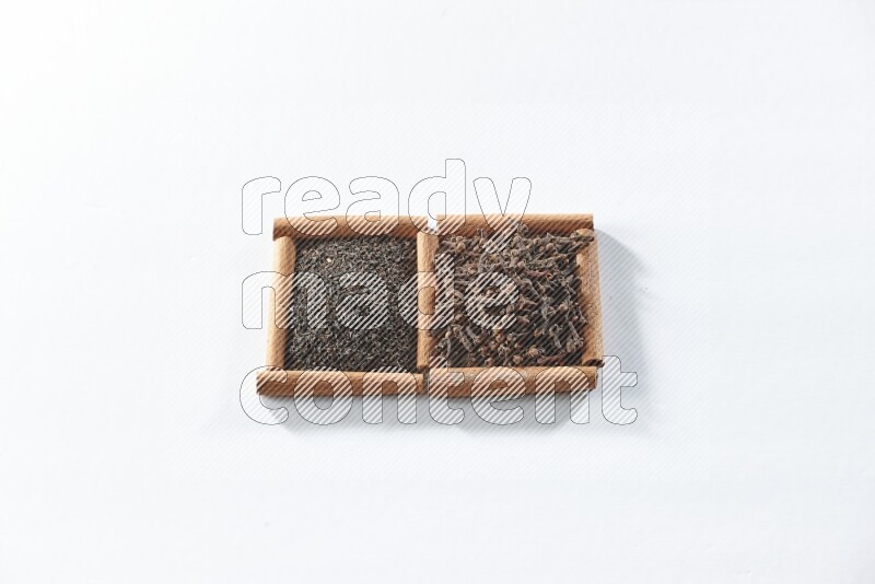 مربعان من أعواد القرفة ممتلئان بالشاي الأسود وحبوب القرنفل علي خلفية بيضاء