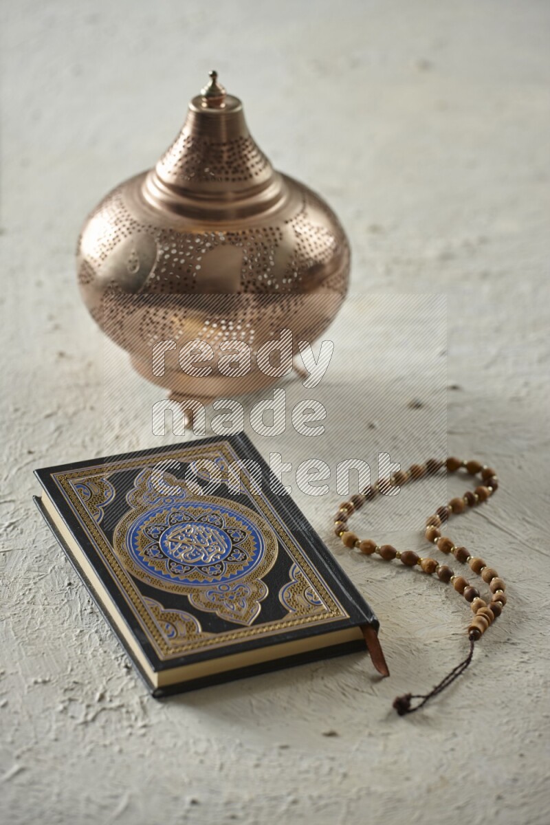 A golden lantern with different drinks, dates, nuts, prayer beads and quran on textured white background