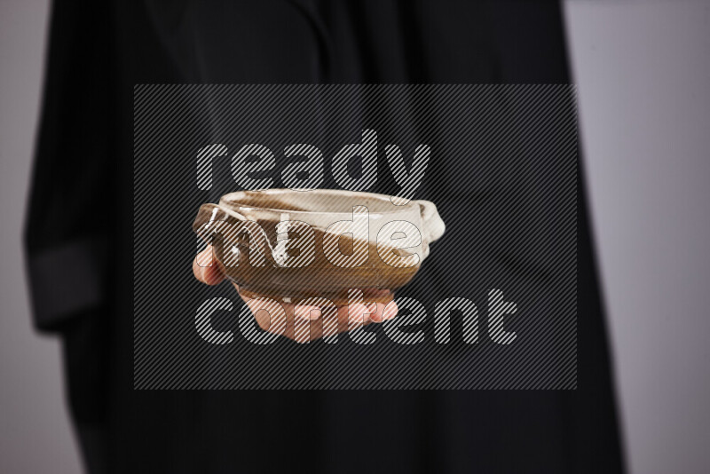 امرأة ترتدي عباءة سوداء تحمل أدوات فخارية مختلفة في أوضاع متعددة