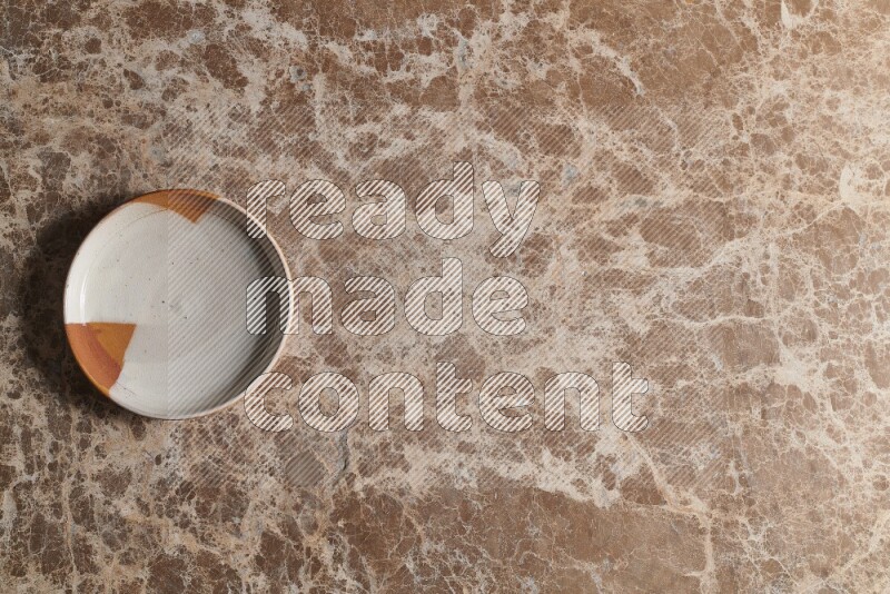 A decorative pottery plate on beige marble background