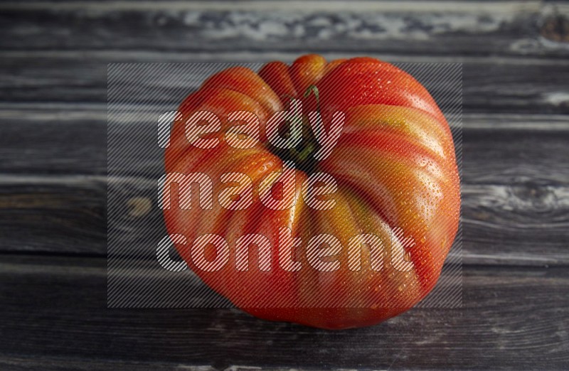 45 degree single heirloom tomato on a textured grey wooden background