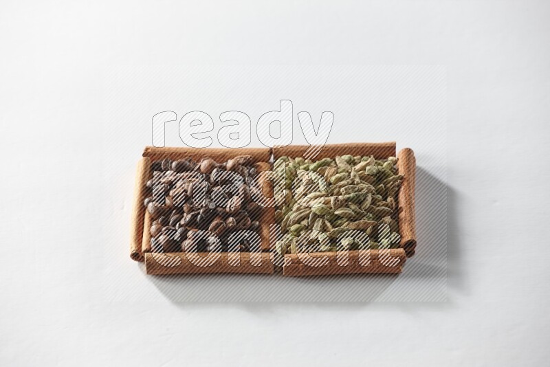 مربعان من أعواد القرفة ممتلئان بحبوب الهيل وحبوب القهوة علي خلفية بيضاء