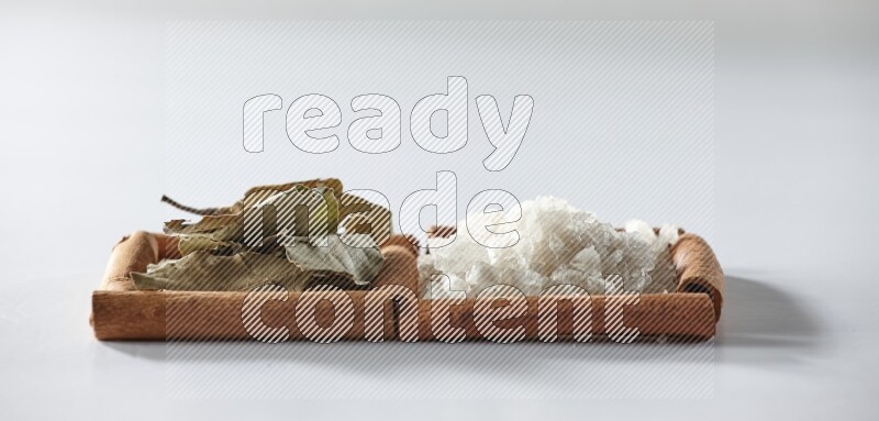 مربعان من أعواد القرفة ممتلئان بالملح الأبيض وأوراق الغار علي خلفية بيضاء