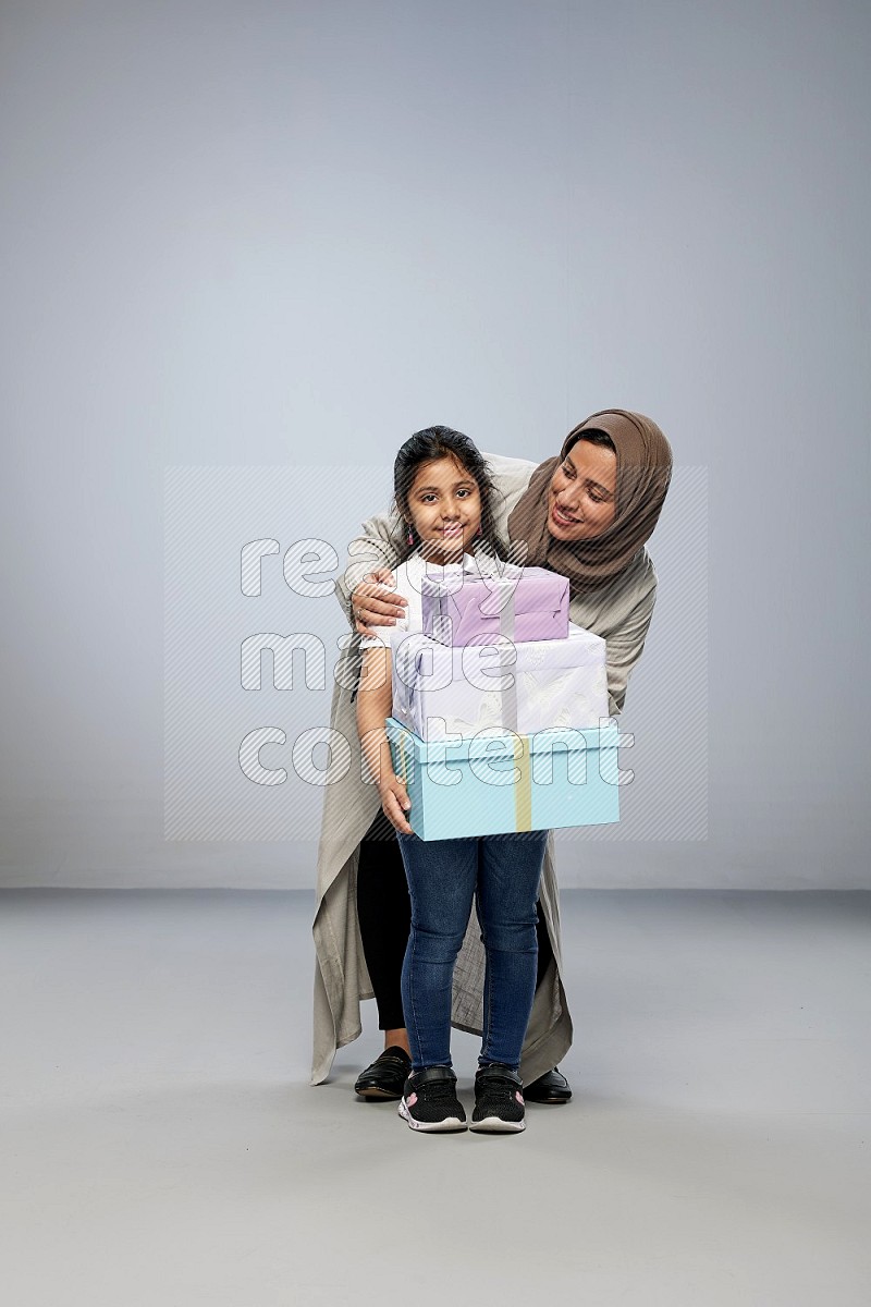 A girl giving a gift to her mother on gray background