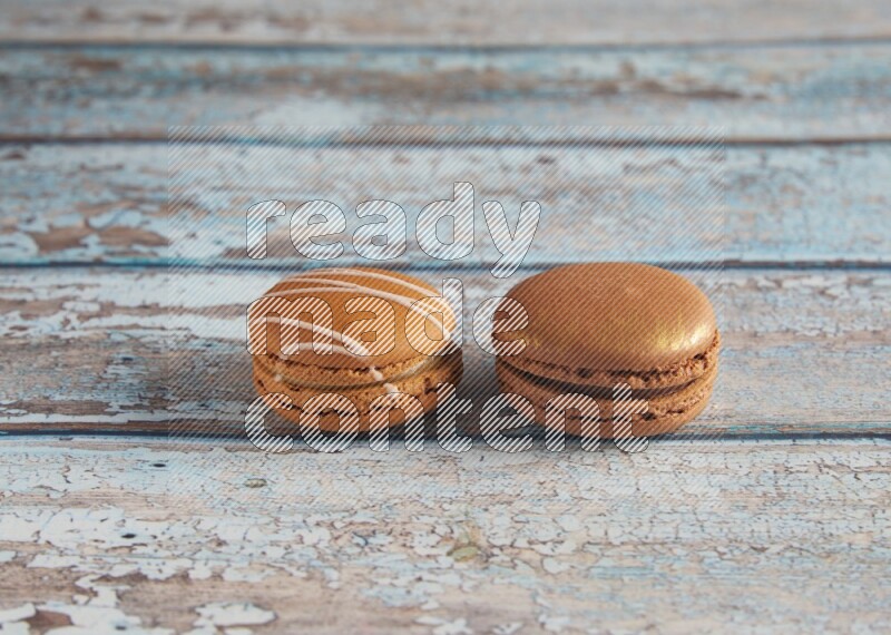 45º Shot of of two assorted Brown Irish Cream, and Brown Coffee macarons on light blue background
