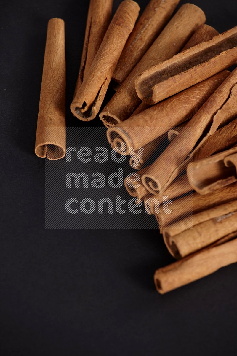 Cinnamon sticks stacked on black flooring