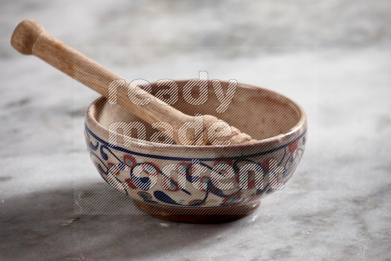 Decorative Pottery Bowl with wooden honey handle in it, on grey marble flooring, 15 degree angle