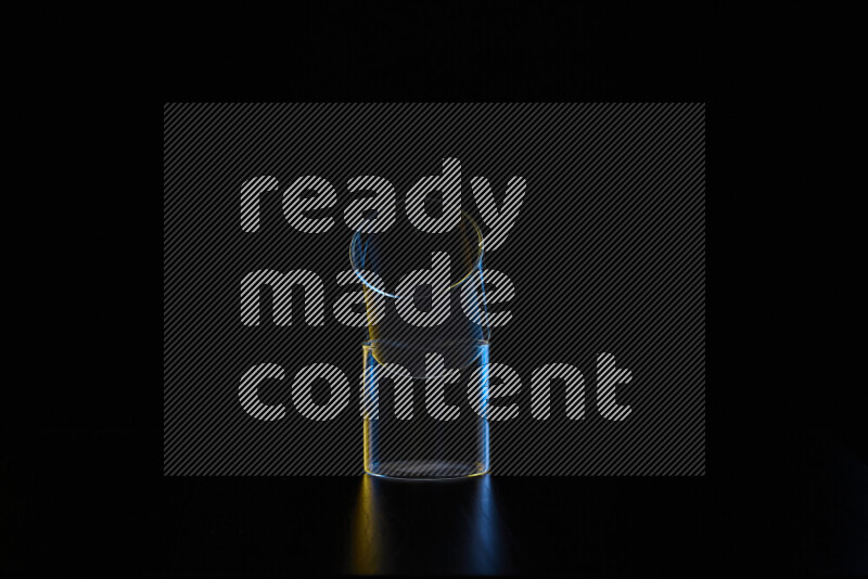 Glassware with rim light in blue and yellow against black background