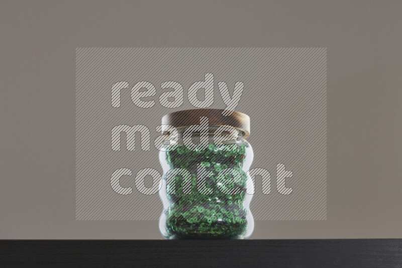 Sequins in a glass jar on black background