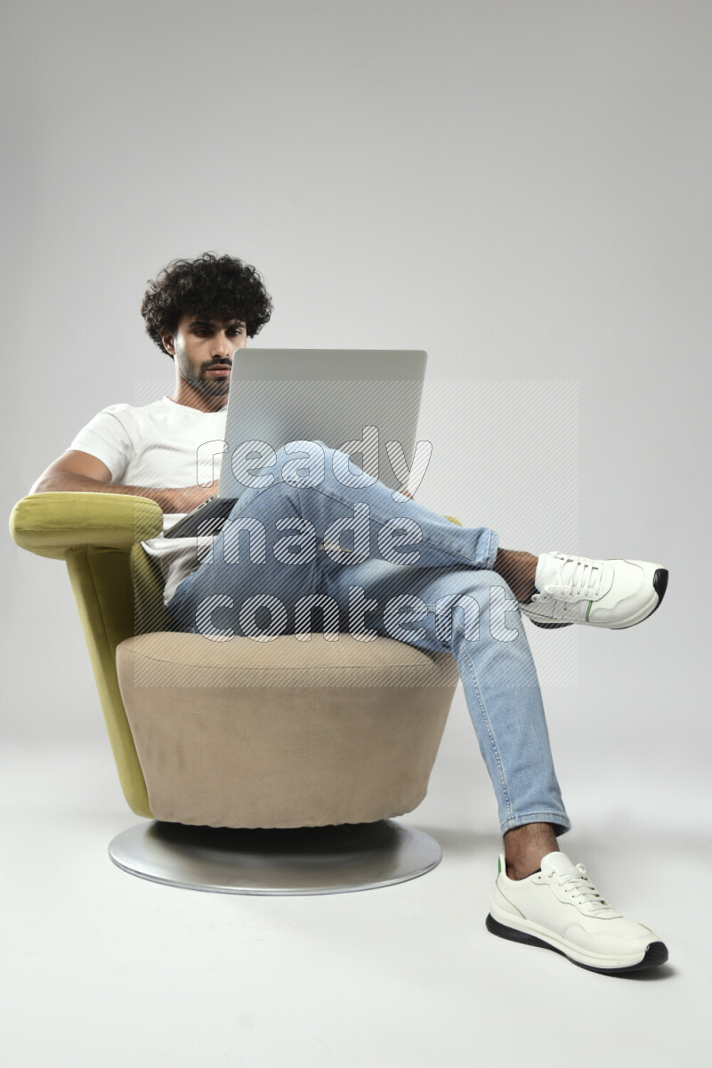 A man wearing casual sitting on a chair working on a laptop on white background