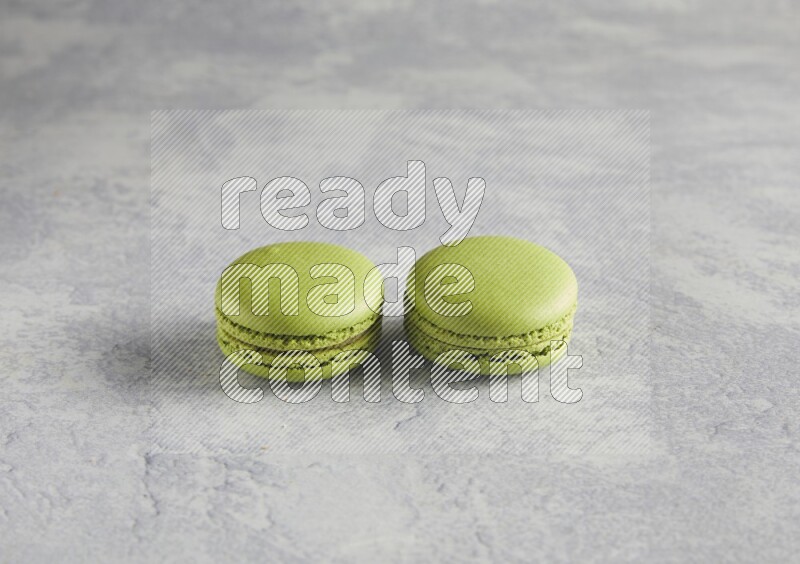 45º Shot of two Green Pistachio macarons  on white  marble background