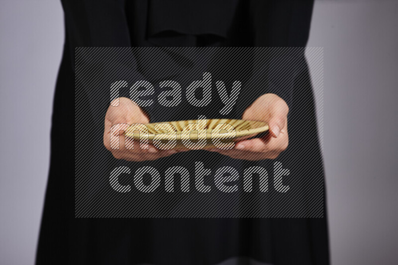 A woman in black abaya holding different pottery essentials in different positions