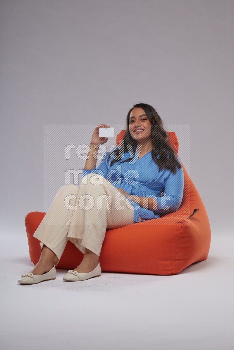 A woman sitting on an orange beanbag and holding ATM card