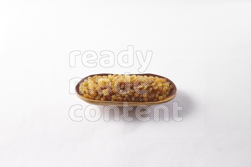 Raisins in a wooden plate on white background