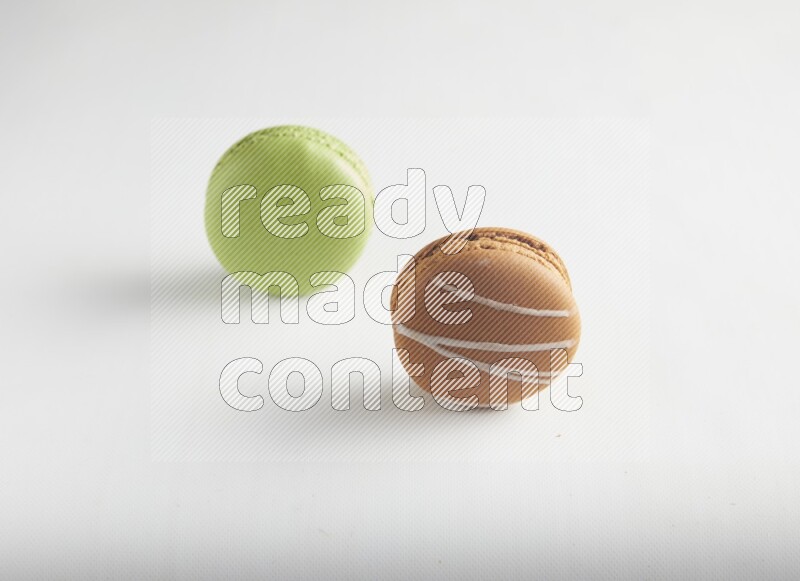 45º Shot of of two assorted Brown Irish Cream, and Green Pistachio macarons on white background