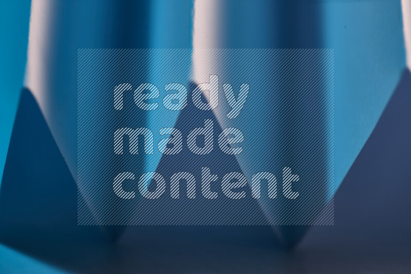 صورة مجردة مقربة تظهر طيات ورقية هندسية حادة بتدرجات اللون الأزرق