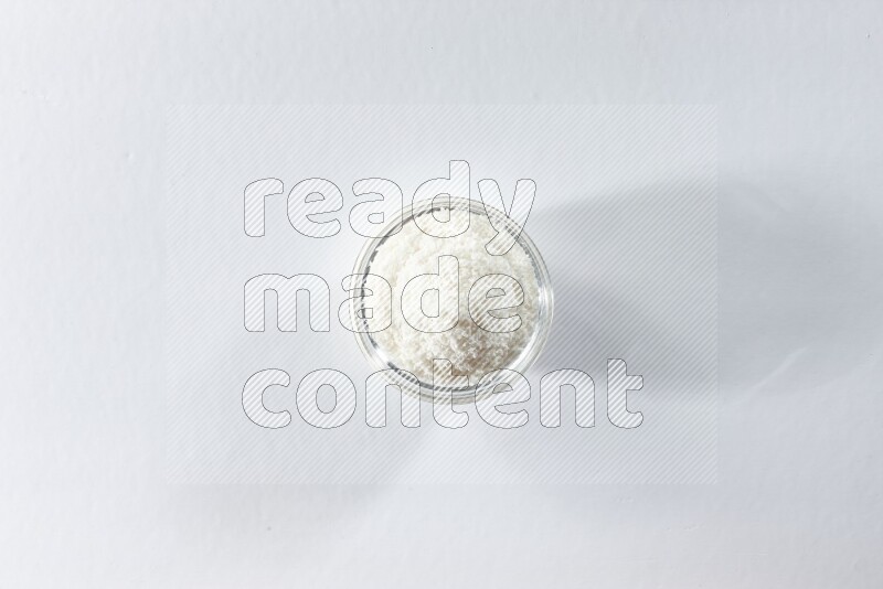 وعاء زجاجي ممتلئ بجوز الهند المجفف المبشورعلى خلفية بيضاء