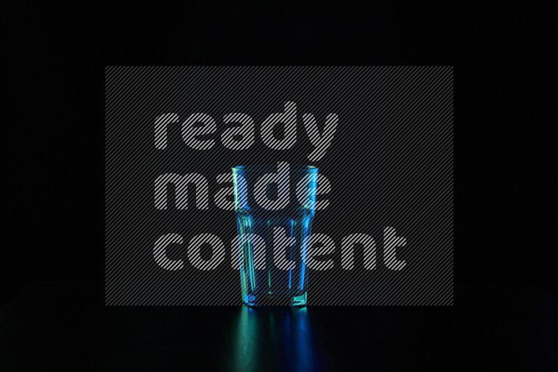 Glassware with rim light in blue and green against black background