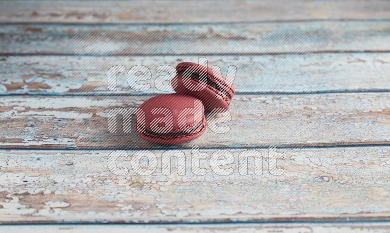 45º Shot of two Red Cherry macarons on light blue wooden background