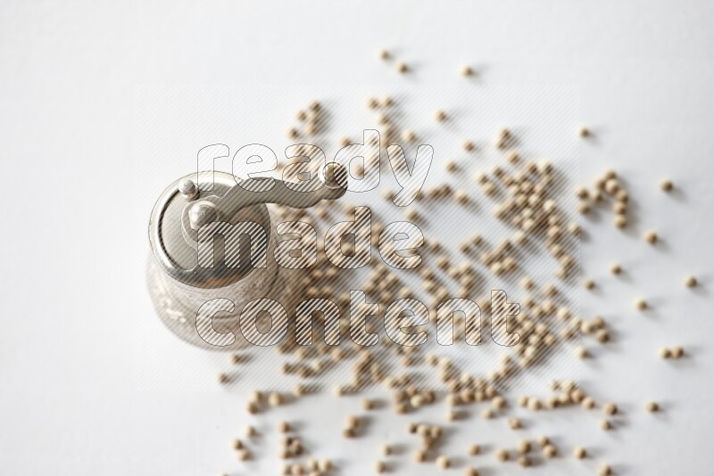 White pepper beads with a metal grinder on white flooring