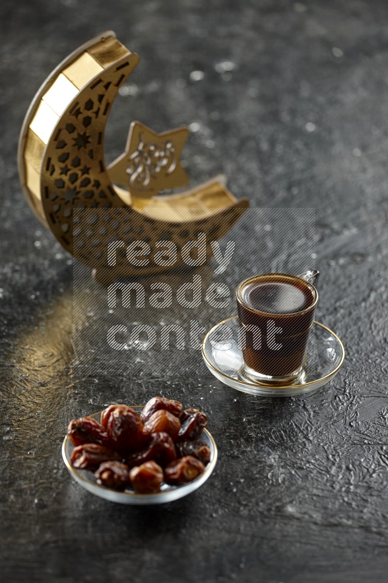 A wooden golden crescent lantern with different drinks, dates, nuts, prayer beads and quran on textured black background