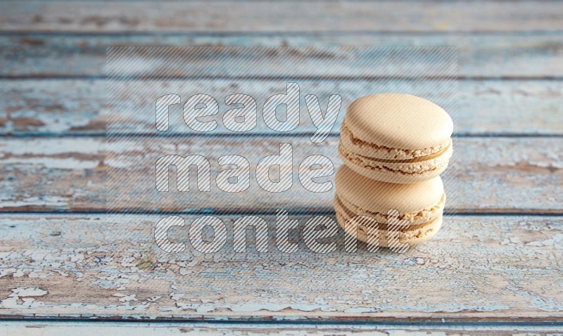 45º Shot of two White Caramel fleur de sel macarons on a light blue wooden background